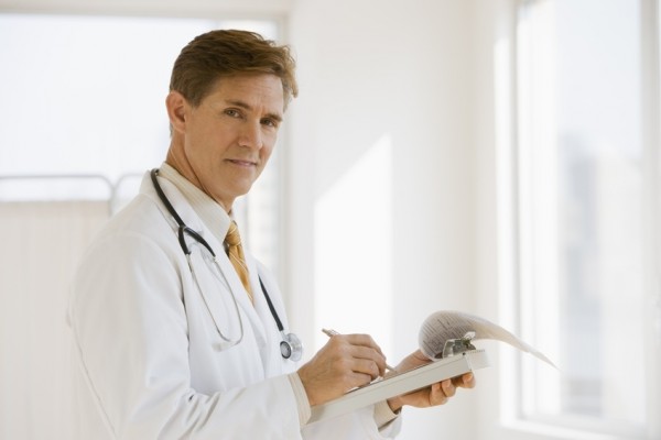 Doctor writing a report and looking at camera
