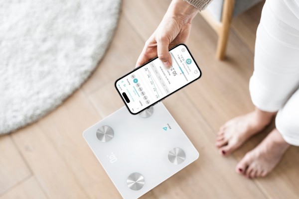 Woman using smartphone next to weighing scale  innovative technology